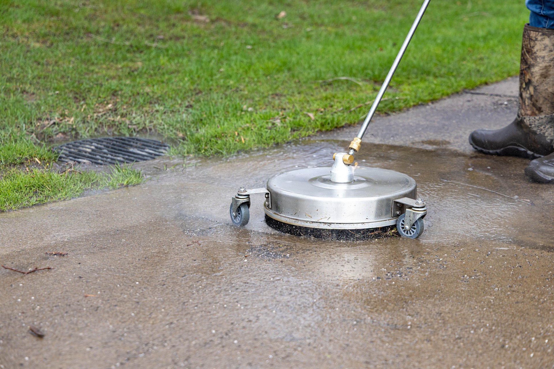Pressure washing a concrete sidewalk with a surface cleaner.